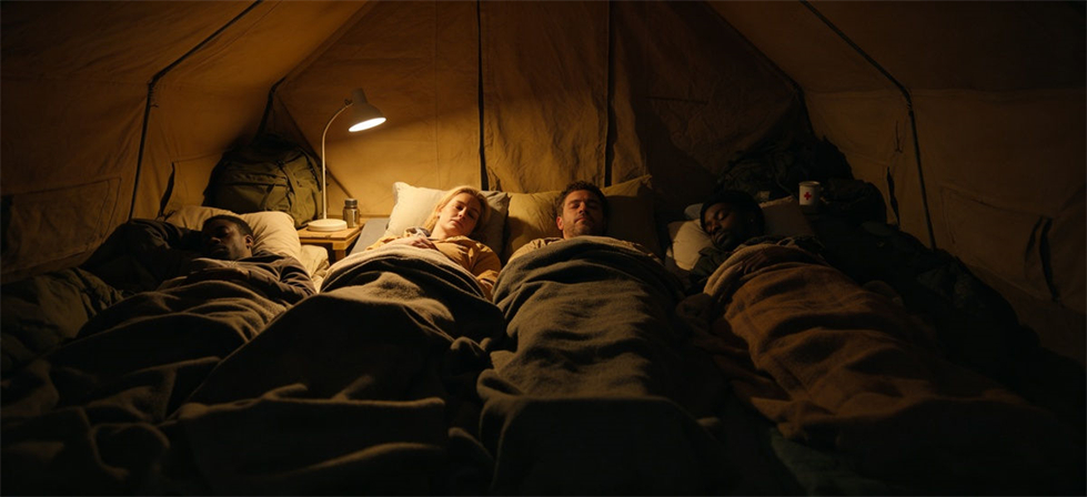 Family using blankets inside a relief tent at night for institutional bulk procurement review