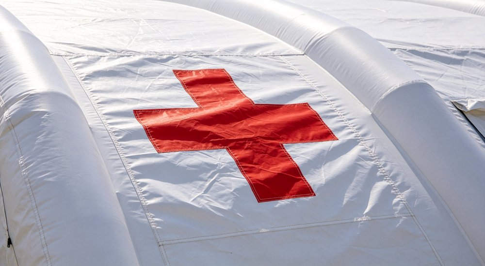 Red cross marking on air beam of inflatable medical tent, close-up detail showing medical ID red and white inflatable emergency shelter for disaster relief operations