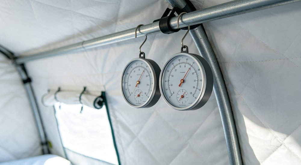 Thermo hygrometer inside inflatable isolation tent, temperature and humidity monitor, product shot red and white inflatable emergency shelter for disaster relief operations