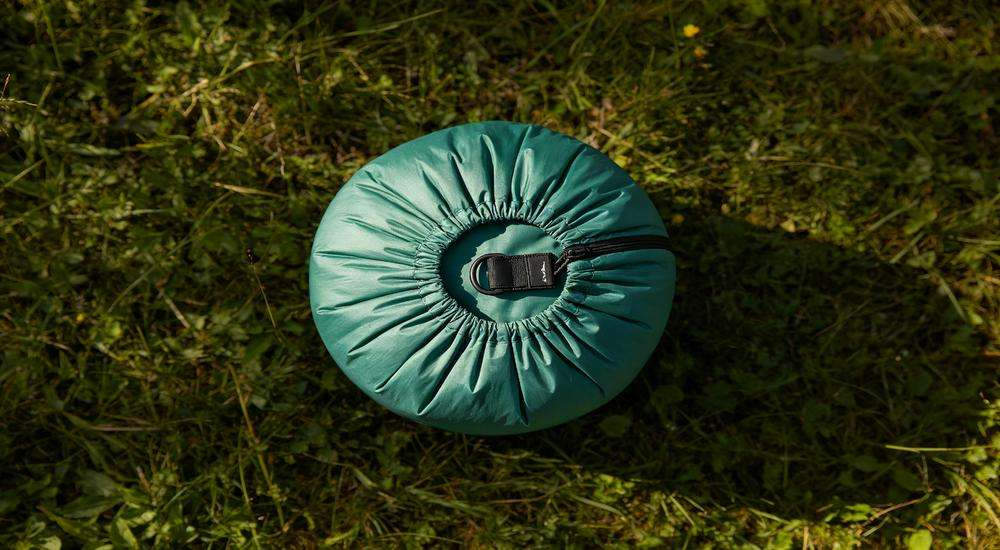 Top view of sleeping bag compression sack accessory, compact storage solution, outdoor gear display on grass