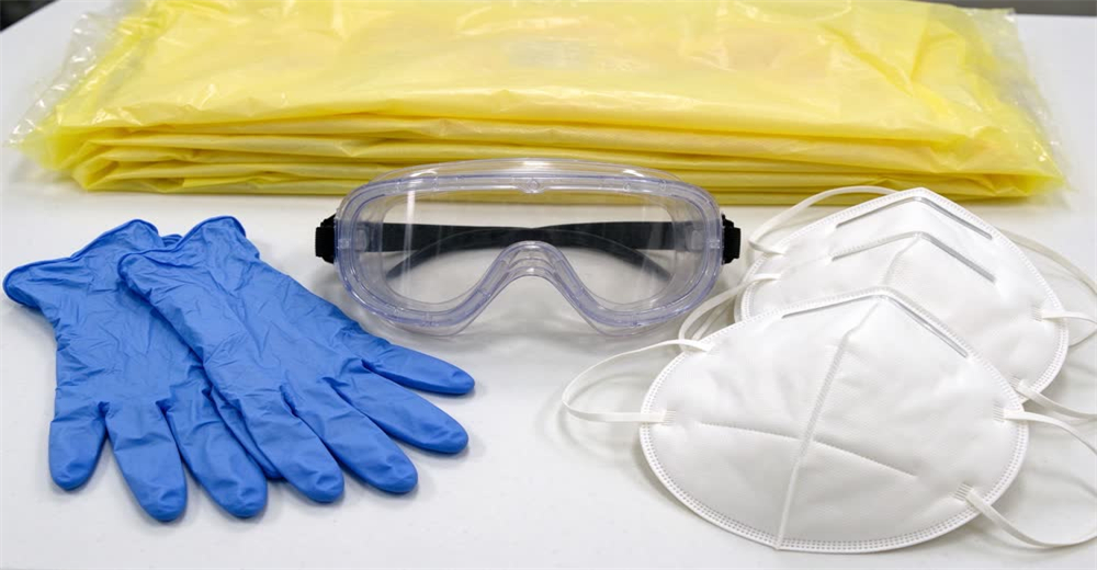 Flat lay PPE family including nitrile gloves surgical masks gowns and face shields showing responder personal protective equipment