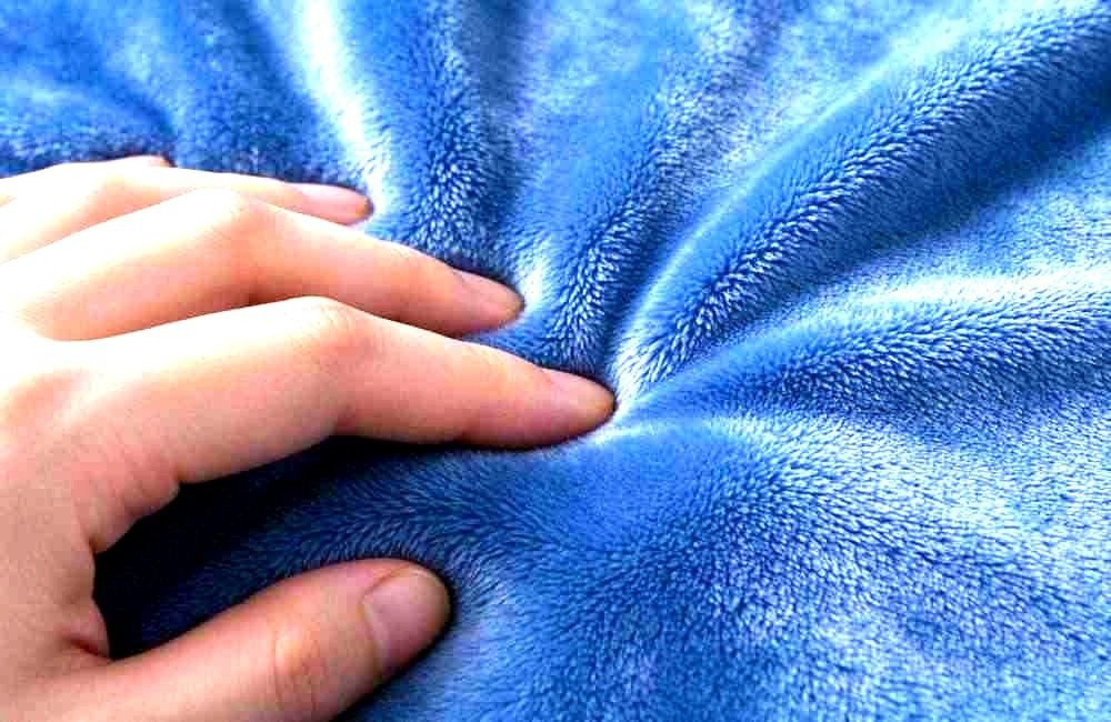Close-up texture view of brushed flannel fabric showing dense soft fibre surface and even weave pattern, neutral lighting, product detail shot